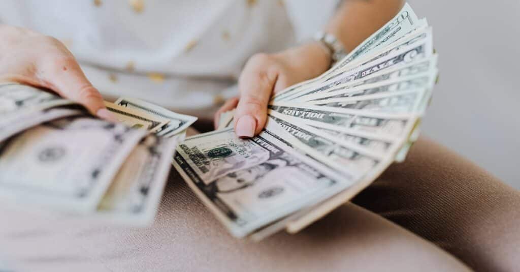 Close-up of hands holding and counting US dollar bills indoors.