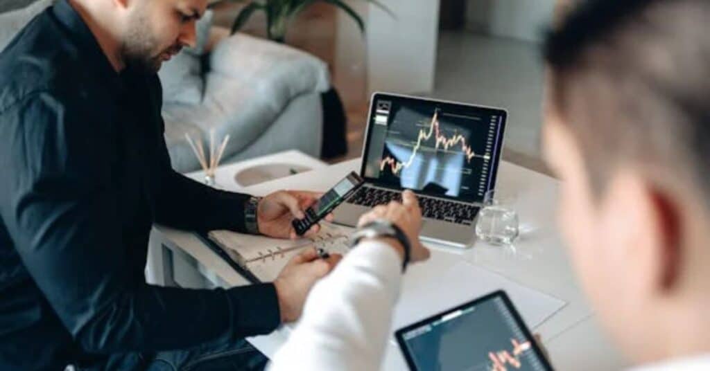 Trader analisando gráficos financeiros em um computador, simbolizando gestão de capital no mercado.